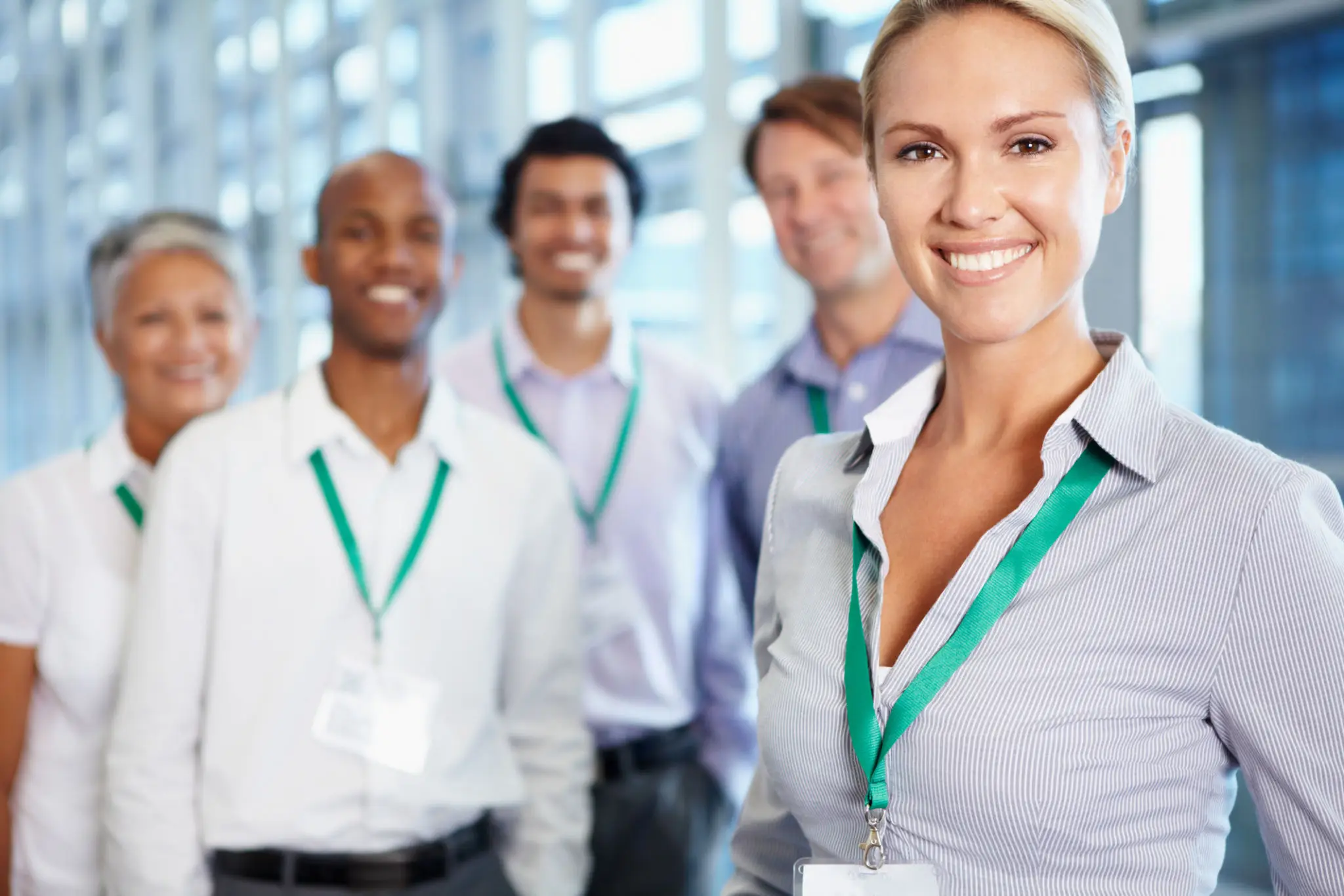 Smiling professionals with ID badges and lanyards.