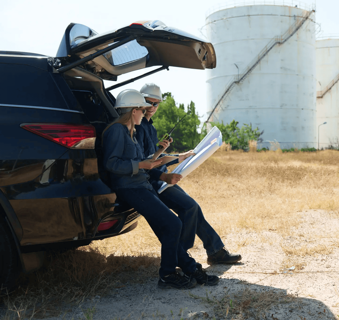 Team examining documents beside a car